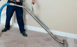 Professional operating a liquid removal machine on a carpeted floor in Detroit, MI